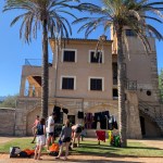 Gruppenaktivität vor einer Finca in Mallorca, mit Palmen im Vordergrund, während Teilnehmer ihre Ausrüstung für das Canyoning Camp vorbereiten.